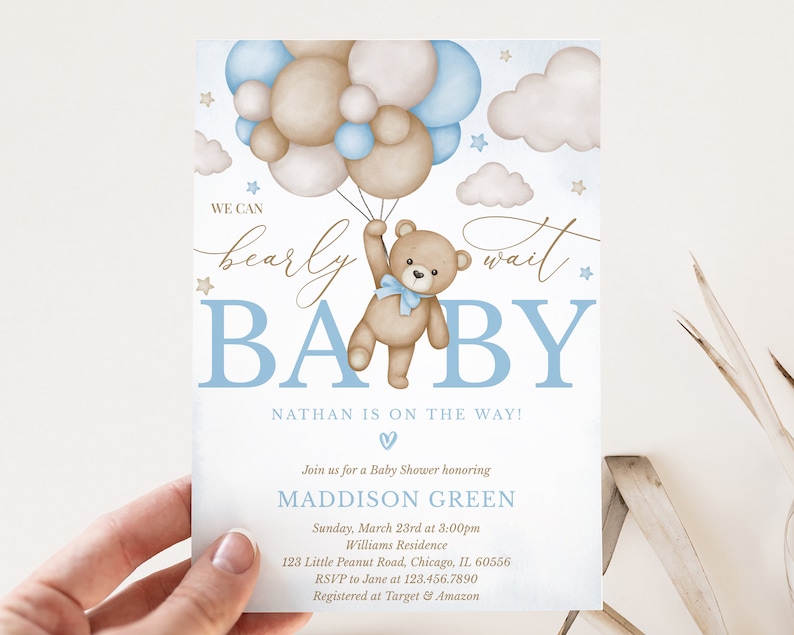 May include: A baby shower invitation featuring a blue and brown colour scheme. A teddy bear holding onto blue and brown balloons is at the centre of the invitation. The text "We can barely wait BABY" is written in a cursive font. The text "Nathan is on the way!" is written in a bold font. The invitation includes the date, time, and location of the baby shower.