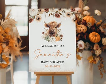 Puede incluir: Bienvenido a la fiesta de bienvenida al bebé de Samantha con una ilustración de acuarela de una vaca de las tierras altas con una corona de flores y calabazas. El cartel está en un caballete de madera y tiene un fondo de purpurina dorada.