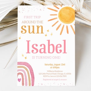 Pu&ograve; includere: Un arcobaleno acquerellato rosa e arancione con un cuore bianco al centro. Il testo "FIRST TRIP AROUND THE sun Isabel IS TURNING ONE!" &egrave; stampato in oro e rosa. L'invito &egrave; per una festa di primo compleanno il 23 agosto alle 16:00. L'indirizzo, le informazioni RSVP e i dettagli del registro sono inclusi.