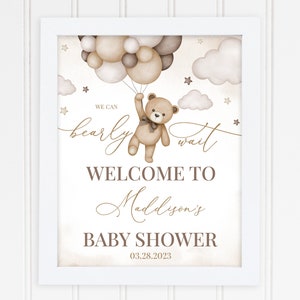 K&ouml;nnte beinhalten: Ein brauner Teddyb&auml;r, der Ballons h&auml;lt, mit dem Text "We can bearly wait" und "Welcome to Madison's Baby Shower 03.28.2023".