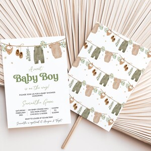 May include: Baby shower invitation and matching card featuring a watercolor design. The invitation reads "A sweet Baby Boy is on the way!" with details for the event. The design includes baby clothes and accessories hanging on a clothesline.
