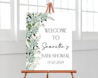 May include: A white welcome sign with a green succulent floral design. The sign reads "Welcome to Samantha's Baby Shower 01-23-2024".