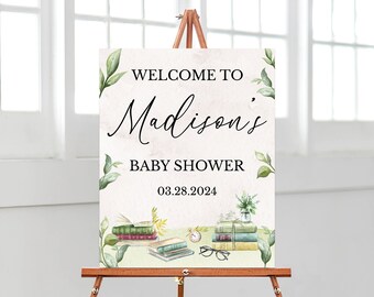 May include: A rectangular welcome sign for a baby shower featuring the text WELCOME TO Madison's BABY SHOWER 03.28.2024. The design includes watercolour illustrations of green leaves, stacks of books, a small clock, and spectacles.