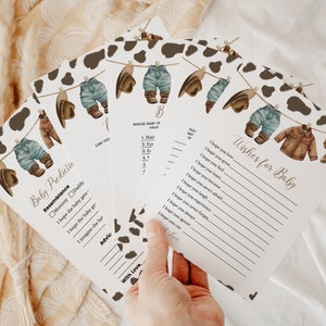 May include: A set of printable baby shower game cards with a cowboy theme. The cards feature a line of clothes hanging on a clothesline with a cow print background. The text on the cards includes "Baby Predictio", "Resemblance", "Mommy Daddy", "I hope the baby gets", "I hope the baby ge", "I imagine the bal", "Advic", "CAN YOU", "B", "WHOSE BABY IT HAVE", "1. Hair", "2. Eyr", "3. Er", "47", "With Love,", "Wishes for Baby", "I hope you love,", "I hope you grow", "I hope you find.", "I hope you leurs", "I hope you become", "I hope you aren't afraid.", "I hope you laugh", "I hope you experience", "I hope you never forget", "I hope you always", "I hope you igoure", "I hope you can"