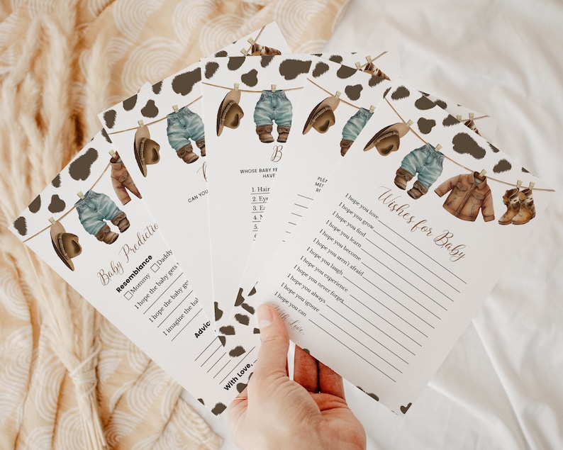 May include: A set of printable baby shower game cards with a cowboy theme. The cards feature a line of clothes hanging on a clothesline with a cow print background. The text on the cards includes "Baby Predictio", "Resemblance", "Mommy Daddy", "I hope the baby gets", "I hope the baby ge", "I imagine the bal", "Advic", "CAN YOU", "B", "WHOSE BABY IT HAVE", "1. Hair", "2. Eyr", "3. Er", "47", "With Love,", "Wishes for Baby", "I hope you love,", "I hope you grow", "I hope you find.", "I hope you leurs", "I hope you become", "I hope you aren't afraid.", "I hope you laugh", "I hope you experience", "I hope you never forget", "I hope you always", "I hope you igoure", "I hope you can"