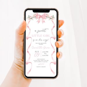 May include: A pink and white baby shower invitation with a pink bow and floral design. The text reads "a sweet little girl is on her way!" and includes the date and time of the event.