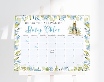 May include: A rectangular sign featuring a calendar for April and May with the text GUESS THE ARRIVAL OF Baby Chloe. The design includes a watercolour illustration of a rabbit in a blue jacket, surrounded by a border of blue flowers and green leaves.