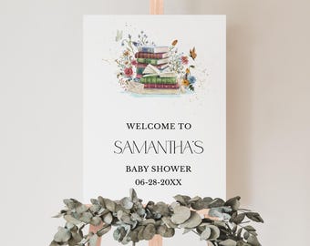 May include: A white sign with a watercolor illustration of a stack of books with flowers and butterflies. The sign says "Welcome to Samantha's Baby Shower 06-28-20XX".