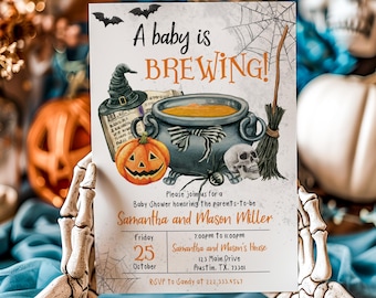 Puede incluir: Invitación a un baby shower con temática de Halloween con una ilustración de un caldero, una calabaza y una calavera. La invitación dice "A baby is BREWING!" e incluye los detalles del evento para Samantha y Mason Miller.