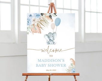 May include: Welcome to Maddison's Baby Shower sign featuring a blue and white watercolour elephant holding balloons. The sign has a floral design with a light blue and white colour scheme.