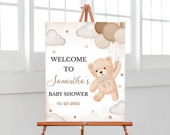 May include: Welcome to Samantha's Baby Shower sign with a teddy bear holding balloons, clouds, and stars on a beige background. The date of the shower is 01-23-2024.