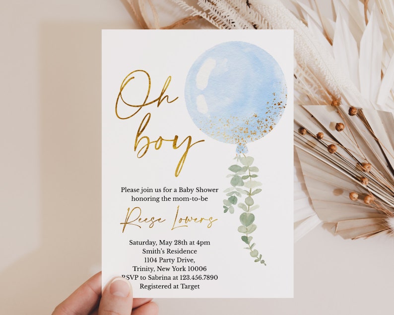 May include: A blue and gold baby shower invitation with a watercolor balloon and eucalyptus leaves. The text reads "Oh boy" in gold script and includes details about the event, including the date, time, location, and RSVP information.