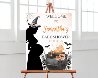 May include: A rectangular sign featuring a black silhouette of a pregnant person wearing a witch hat with a skull. The text reads WELCOME TO Samantha's BABY SHOWER 10-28-20XX. It includes a black cauldron with orange liquid, bats, and roses.