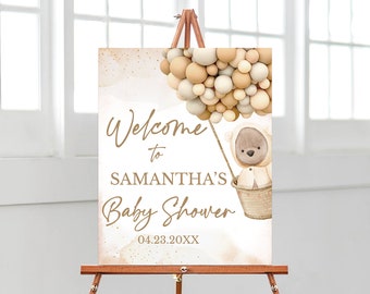 May include: Welcome to Samantha's Baby Shower sign featuring a brown teddy bear in a hot air balloon made of beige and brown balloons. The date 04.23.20XX is printed on the sign.