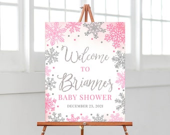May include: Welcome to Brianne's Baby Shower sign with a pink and silver snowflake design. The sign says "Welcome to Brianne's Baby Shower December 23, 2021".