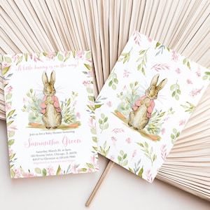 Pu&ograve; includere: Un invito a una festa di benvenuto per un bambino con un'illustrazione ad acquerello di un coniglio che indossa una giacca rosa. L'invito ha un motivo floreale rosa e verde e il testo "A little bunny is on the way!" e "Join us for a Baby Shower honoring Samantha Green".