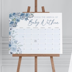 以下が含まれることがあります： 青と白の花柄のベビーシャワーゲーム。ゲームは、「Baby Nathan の到着を予想しよう」というテキストが上部に書かれたカレンダーです。出産予定日はカレンダーに丸で囲まれています。