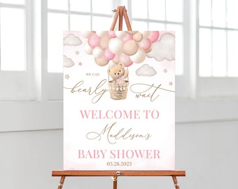 Op de afbeelding: Een roze en beige welkomstbord voor een babyshower met een teddybeer in een luchtballon. Het bord zegt "We can bearly wait" en "Welcome to Maddison's Baby Shower 03.28.2023".