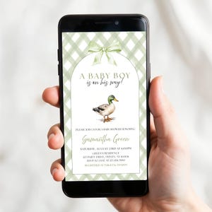Peut inclure: Un &eacute;cran de smartphone affichant une invitation &agrave; une f&ecirc;te pr&eacute;natale avec un fond &agrave; carreaux vert sauge, un n&oelig;ud vert clair et une illustration de canard colvert. Le texte indique : A BABY BOY is on his way! PLEASE JOIN US FOR A BABY SHOWER.