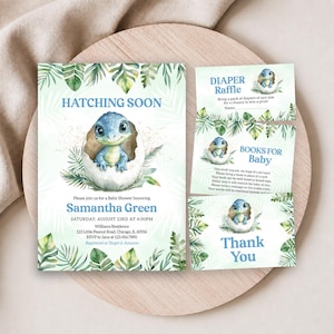 May include: A baby shower invitation set featuring a blue dinosaur hatching from an egg, surrounded by green tropical leaves. The text includes HATCHING SOON, Samantha Green, Saturday, August 23rd at 4:00PM, Diaper Raffle, Books for Baby, and Thank You.