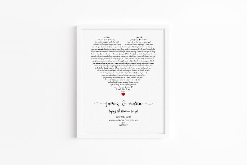 May include: A framed print with a heart-shaped design composed of song lyrics. The names "James & Maria" and "Happy 1st Anniversary!" are written below the heart. A small red heart is at the bottom of the heart-shaped lyrics.