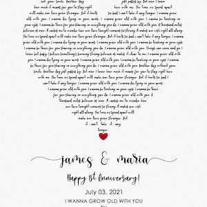 May include: A heart-shaped print with song lyrics, a red heart, and the names "James & Maria." The text reads "Happy 1st Anniversary!" and "July 03, 2021." The song title is "I Wanna Grow Old With You" by Westlife.
