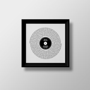 May include: A black and white framed print of a record with lyrics printed in a spiral pattern. The record label says "SONG TITLE" and "SONG ARTIST". The text below the label says "JOHN JOHNSON" and "HAPPY 1ST ANNIVERSARY".