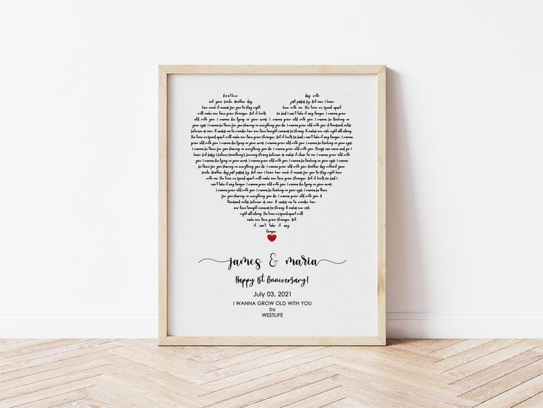 May include: A framed print with a heart-shaped design composed of song lyrics. The print includes the names "James & Maria", the text "Happy 1st Anniversary!", the date "July 03, 2021", and the song title "I WANNA GROW OLD WITH YOU" by WESTLIFE.