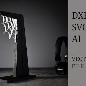 May include: Black headphone stand with a spiderweb design. The stand is made of wood and has a black finish. The spiderweb is made of metal and is attached to the stand. The stand is on a gray surface.  DXF SVG AI VECTOR FILE