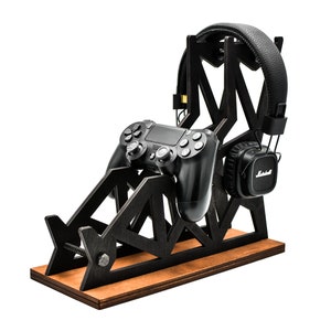 May include: Black wooden stand with a geometric design, holding a black wireless game controller and black headphones with the word "Marshall" on the side.