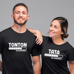 May include: Two black t-shirts with white text and a progress bar graphic. The text on the left shirt reads "Tonton en chargement..." and the text on the right shirt reads "Tata en chargement..."