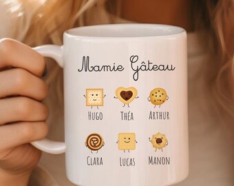 May include: White ceramic mug with the text "Mamie Gâteau" and illustrations of different cookies with names below each: Hugo, Thea, Arthur, Clara, Lucas, Manon.