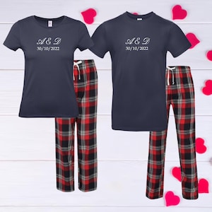 May include: A matching set of navy blue pajamas with red and black plaid pants. The shirts have the text "A & D 30/10/2022" printed on them.