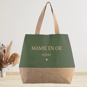 K&ouml;nnte beinhalten: Eine gr&uuml;ne und braune Einkaufstasche mit dem Text "MAMIE EN OR de Julie" und einem kleinen Herz.