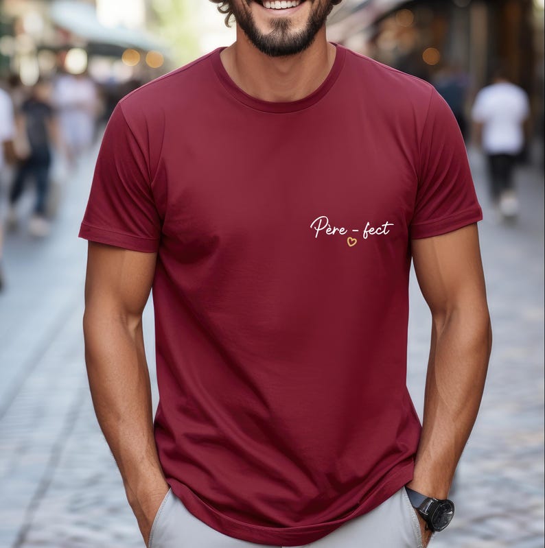 May include: Burgundy crew neck t-shirt with the text "P&egrave;re-fect" in white script and a small gold heart. The shirt is made of a soft material and has short sleeves.