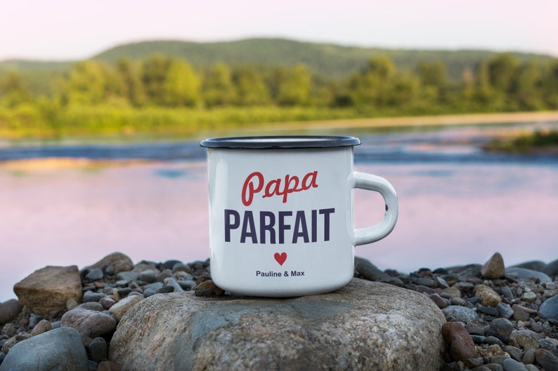 Pu&ograve; includere: Tazza in smalto bianco con bordo e manico neri. La tazza ha testo rosso e blu che dice "Papa Parfait" con un cuore rosso e il testo "Pauline & Max".