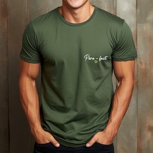 May include: Olive green crew neck t-shirt with rolled sleeves. The shirt features the text "Pere-fect" in a cursive font with a small heart symbol. The shirt is made of a soft, lightweight material.