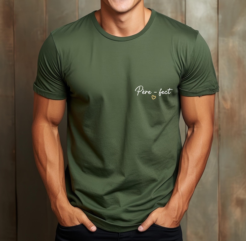 May include: Olive green crew neck t-shirt with rolled sleeves. The shirt features the text "Pere-fect" in a cursive font with a small heart symbol. The shirt is made of a soft, lightweight material.