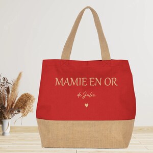 K&ouml;nnte beinhalten: Rote und braune Einkaufstasche mit dem Text "MAMIE EN OR de Julie" und einem kleinen Herz.