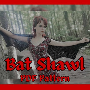 Może przedstawiać: Kobieta w czarnym, szydełkowym szalu w kształcie skrzydeł nietoperza i sukience w kwiatowy wzór. Tekst "Bat Shawl PDF Pattern" jest napisany czerwonymi literami pod kobietą.