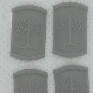 Peut inclure: Quatre plaques décoratives rectangulaires, légèrement incurvées, de couleur grise, avec un motif d'arbre en relief blanc. L'arbre a un tronc épais et de nombreuses branches.