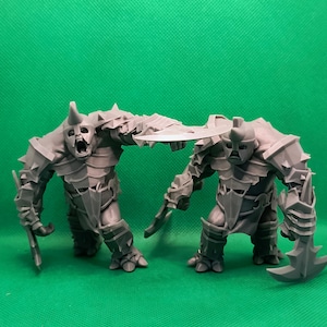 以下が含まれることがあります： 武器と鎧を身につけた2体の灰色のファンタジーオークのフィギュア。1体のオークは、咆哮しているかのように口を開けています。フィギュアは無地の緑色の背景に配置されています。