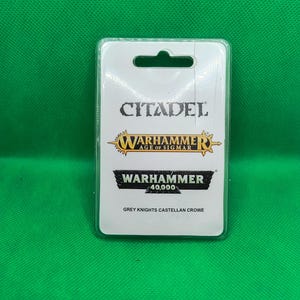 May include: A Citadel Warhammer 40,000 miniature packaging featuring a Grey Knights Castellan Crowe. The packaging is white with black and gold accents.