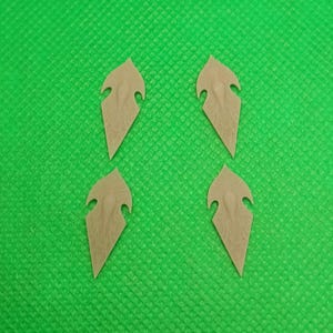 Peut inclure: Quatre composants beiges en forme de bouclier avec une surface texturée et un dessus incurvé avec une découpe. Les composants sont disposés sur un fond vert vif.