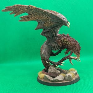 May include: A painted miniature of a griffin, a mythical creature with the head and wings of an eagle and the body of a lion. The griffin is posed in a dynamic stance with its wings spread and its claws extended. The miniature is painted in shades of brown, red, and gold.