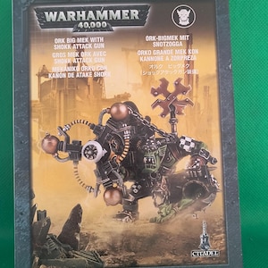May include: A Warhammer 40,000 Ork Big Mek with Shokk Attack Gun box. The box features an illustration of a green-skinned Ork in a mechanical suit wielding a large weapon. The box has text in multiple languages.