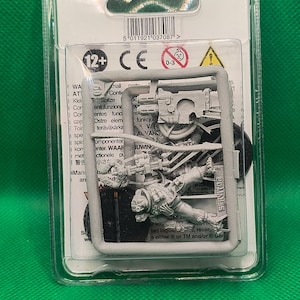 May include: A gray plastic blister pack containing a miniature plastic figure of a space marine. The figure is holding a weapon and is wearing armor. The figure is part of a Warhammer 40,000 game.