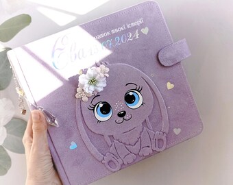 May include: A lavender-coloured scrapbook with a 3D bunny design. The bunny has large blue eyes, a pink nose, and a white flower crown. The cover also has the text "намок твоей истории" and the date "07.2024".