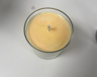May include: A clear glass candle jar with a yellow wax candle and a white wick.