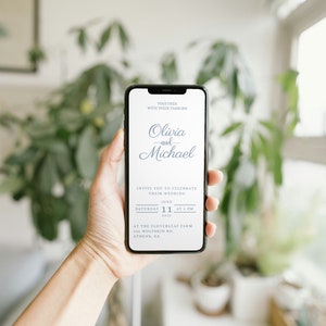 May include: A smartphone displaying a wedding invitation for Olivia and Michael. The invitation is for a wedding on Saturday, June 11th, 2023 at 5 PM at the Cloverleaf Farm in Athens, GA.